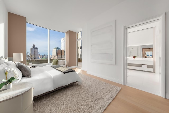 bedroom featuring light wood-style floors, a city view, and a wall of windows