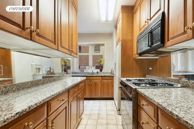 36 Sutton Pl S Unit 2A, New York City, NY 10022 - kitchen with range with gas stovetop, black microwave, brown cabinets, light stone counters, and light tile patterned floors
