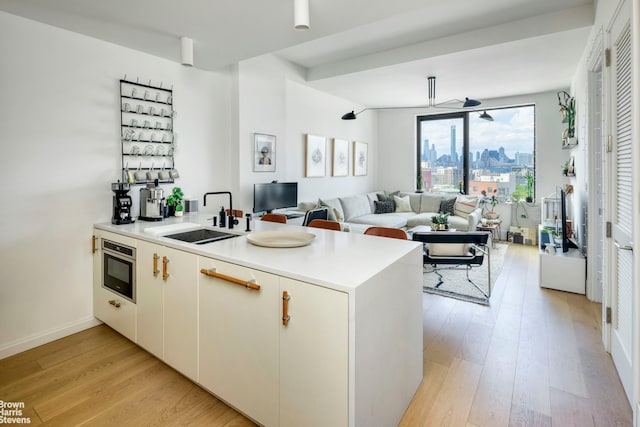 22-18 Jackson Ave Unit 801, New York City, NY 11101 - kitchen with a peninsula, a sink, light wood-type flooring, open floor plan, and light countertops