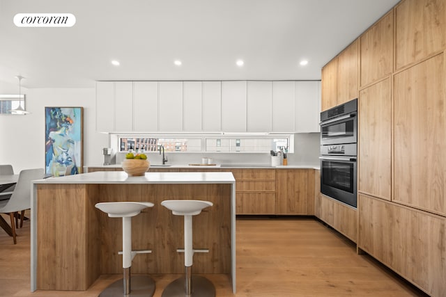 kitchen featuring light countertops, a center island, modern cabinets, a sink, and recessed lighting