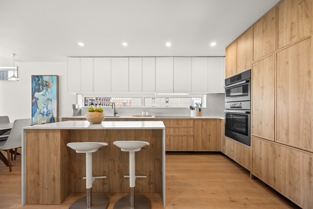 kitchen with a kitchen island, light countertops, modern cabinets, a sink, and recessed lighting
