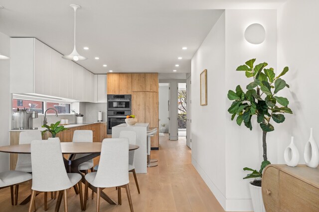 dining room with recessed lighting, light wood-type flooring, and baseboards