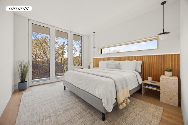 bedroom featuring multiple windows, access to outside, wood finished floors, and expansive windows