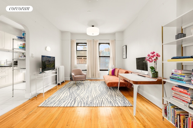 office space with radiator, wood-type flooring, arched walkways, and baseboards