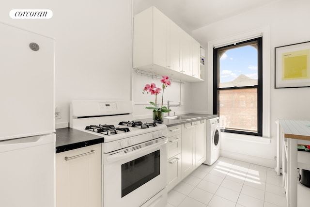 kitchen featuring white appliances, washer / clothes dryer, light tile patterned floors, a sink, and white cabinets