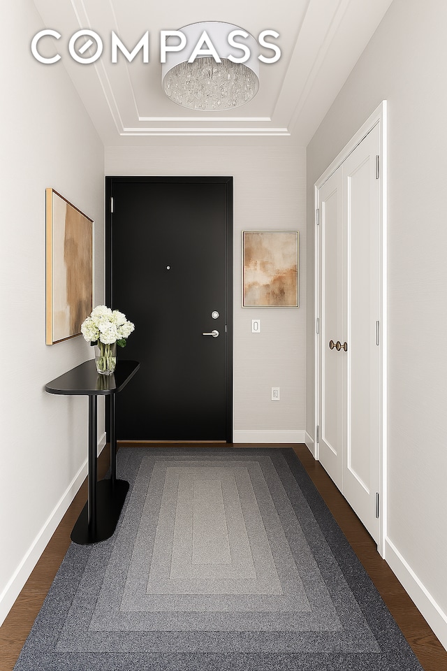 entrance foyer with a tray ceiling, dark wood-style floors, and baseboards
