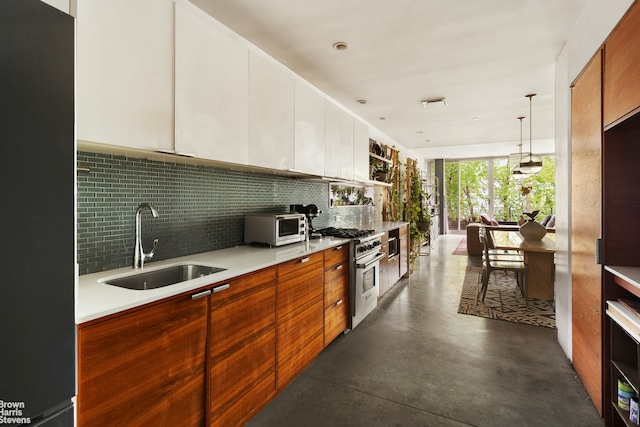 kitchen featuring high end stainless steel range, freestanding refrigerator, a sink, backsplash, and light countertops