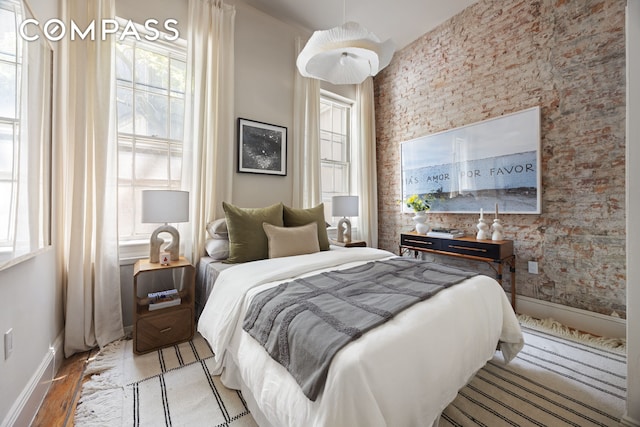 bedroom with multiple windows, baseboards, wood finished floors, and wallpapered walls