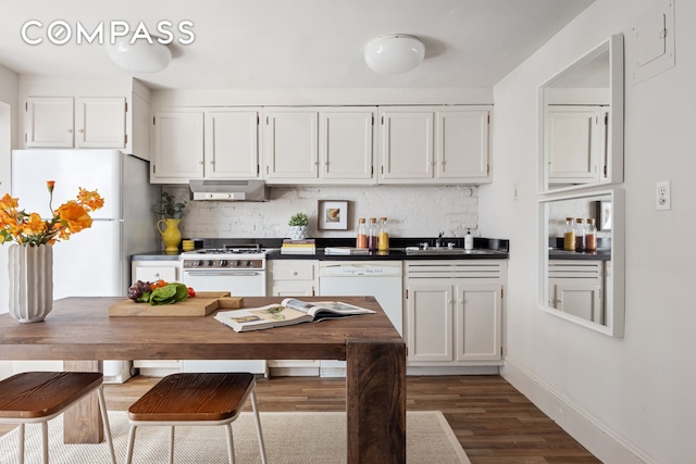 kitchen featuring ventilation hood, dark countertops, decorative backsplash, a sink, and white cabinetry