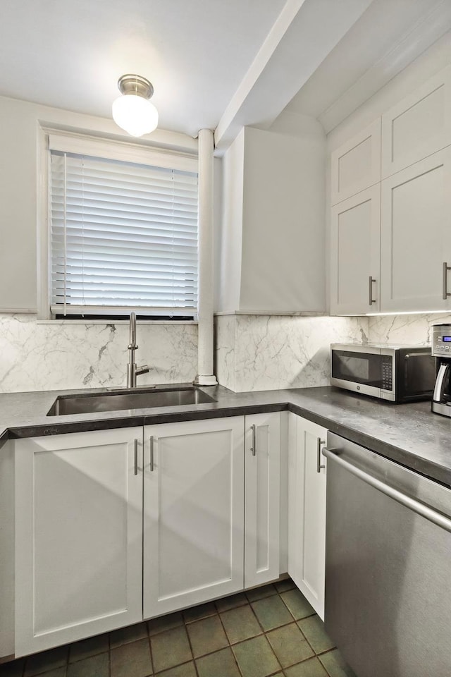 kitchen featuring stainless steel appliances, a sink, dark countertops, and decorative backsplash