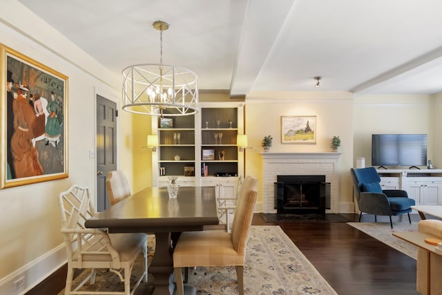 dining space with dark wood-style floors, a chandelier, a fireplace, and baseboards