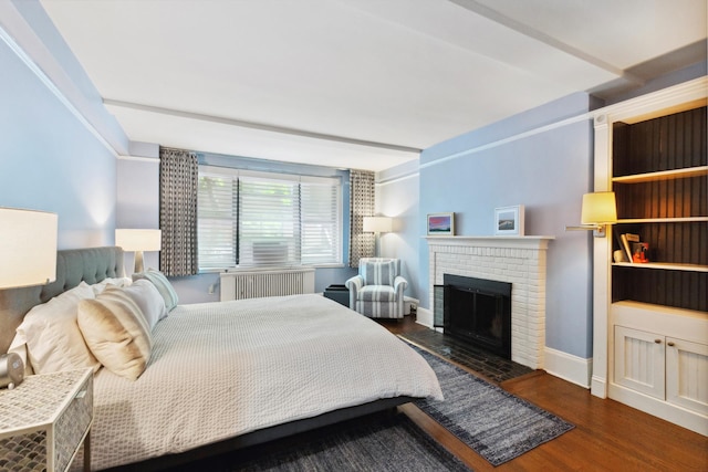 bedroom with radiator, baseboards, wood finished floors, and a fireplace