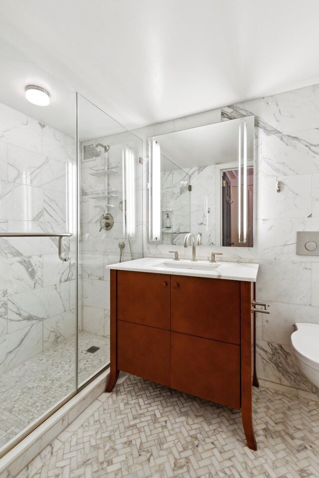 full bathroom with a marble finish shower, tile walls, toilet, and vanity