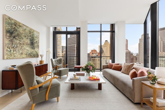living room with a view of skyline, expansive windows, and light wood-style flooring