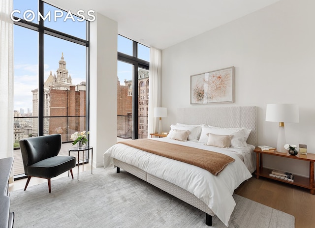 bedroom featuring expansive windows, wood finished floors, and a city view