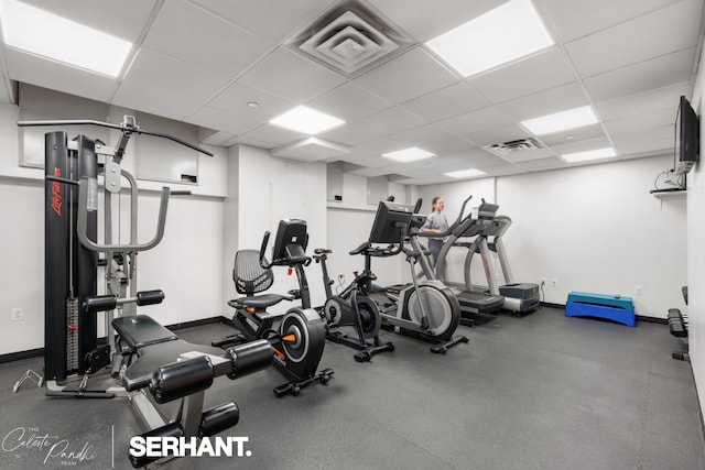 exercise room with a drop ceiling and baseboards