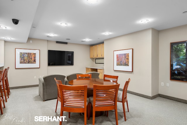 dining area featuring light carpet and baseboards
