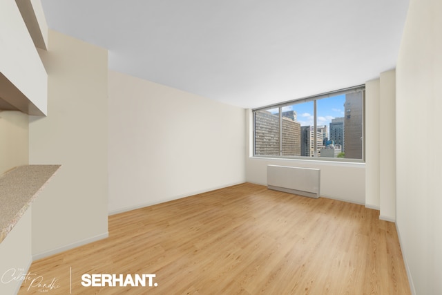 250 E 30th St Unit 8D, New York City, NY 10016 - spare room featuring light wood finished floors, radiator, and baseboards