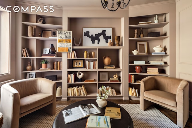 living area featuring ornamental molding, built in shelves, and a chandelier