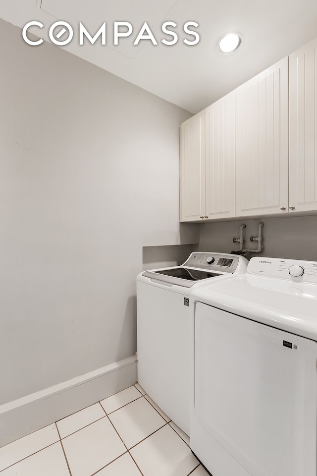 138 W 73rd St, New York City, NY 10023 - laundry area featuring cabinet space, washer and clothes dryer, light tile patterned floors, and baseboards