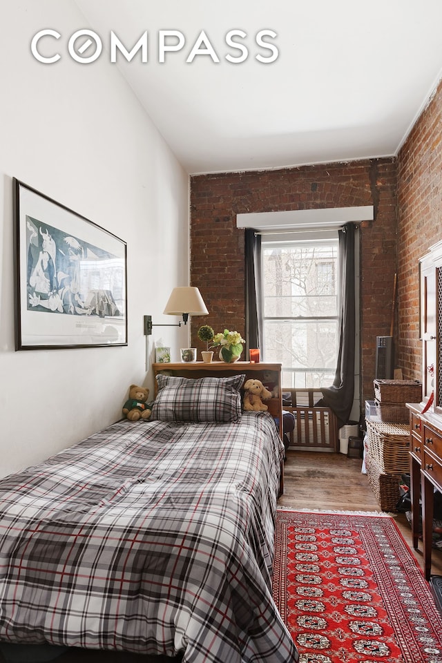 138 W 73rd St, New York City, NY 10023 - bedroom featuring brick wall and light wood-type flooring