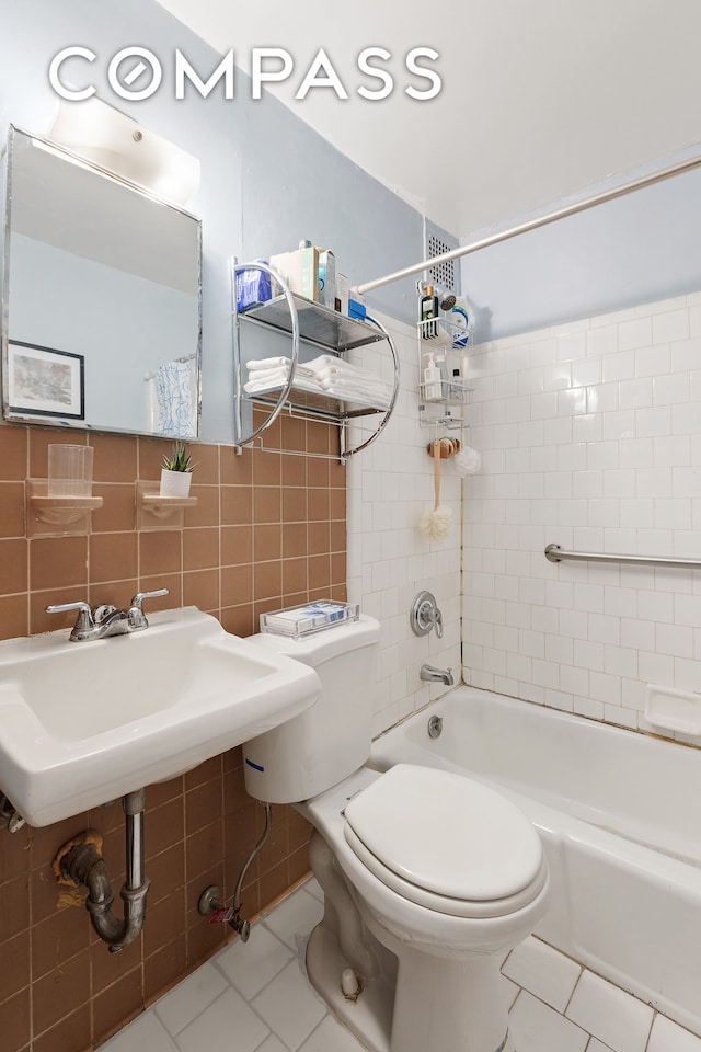 138 W 73rd St, New York City, NY 10023 - full bathroom featuring tile walls, tile patterned floors, toilet, bathtub / shower combination, and a sink
