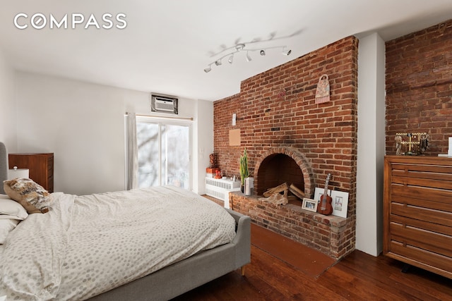 138 W 73rd St, New York City, NY 10023 - bedroom with dark wood-type flooring, a brick fireplace, brick wall, and a wall unit AC