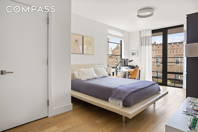bedroom featuring access to outside, light wood-style flooring, and floor to ceiling windows