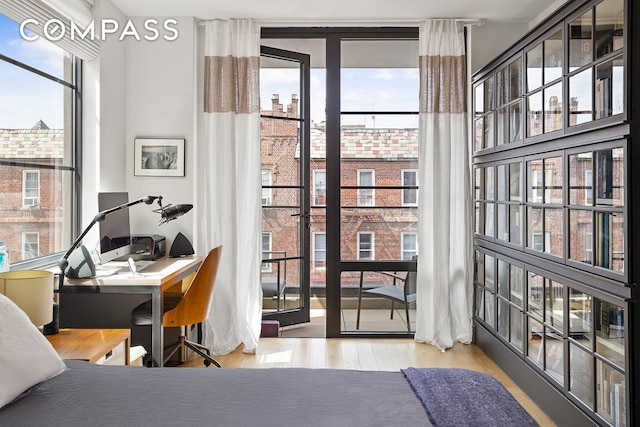bedroom with a desk, wood finished floors, and expansive windows