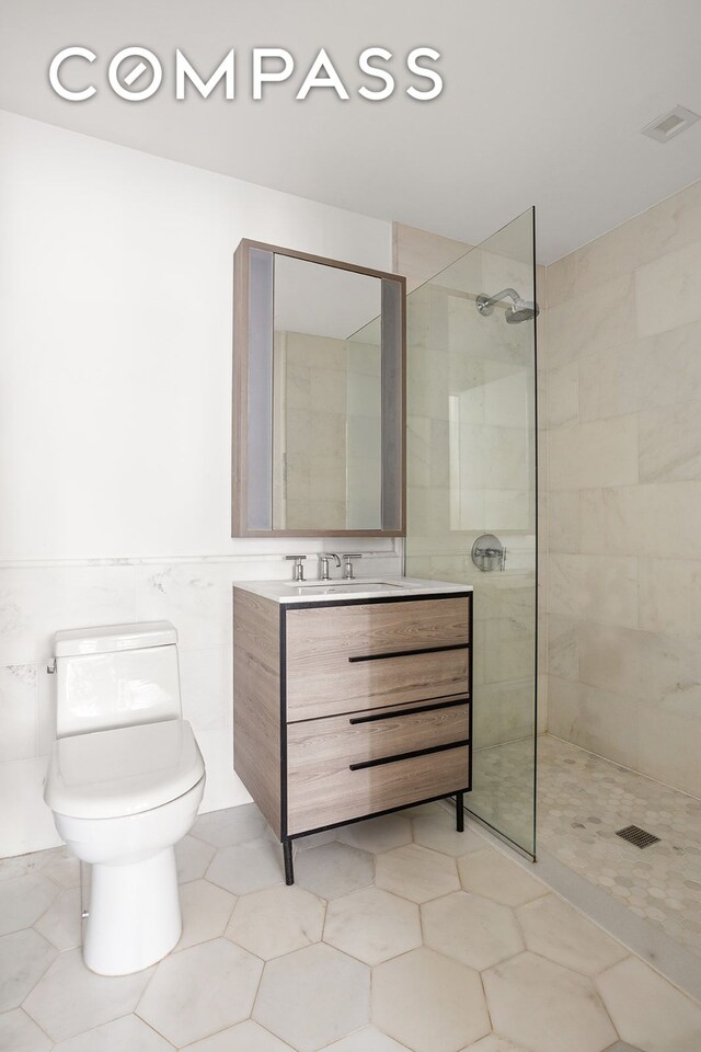 bathroom featuring tile walls, vanity, a walk in shower, toilet, and tile patterned floors
