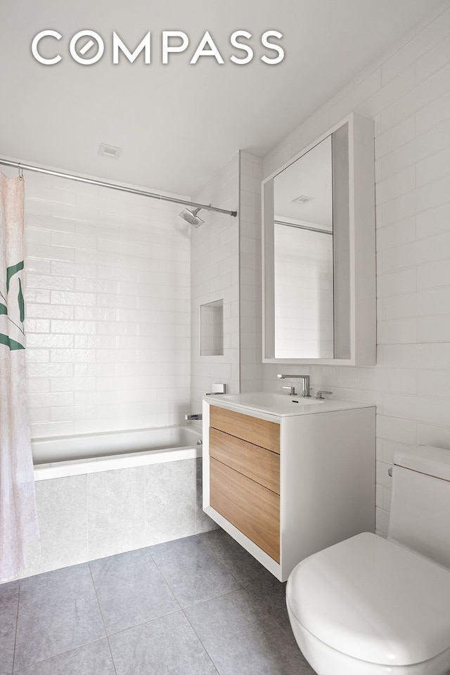 full bathroom featuring toilet, tile patterned flooring, tiled shower / bath combo, and vanity
