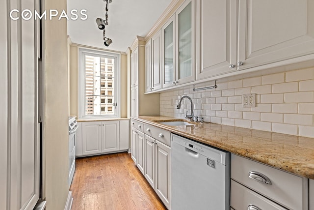 245 E 54th St Unit 25St, New York City, NY 10022 - kitchen featuring dishwashing machine, a sink, light wood-type flooring, tasteful backsplash, and glass insert cabinets