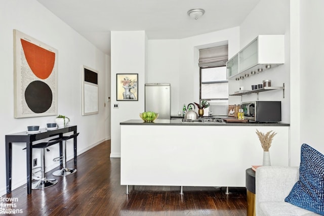 323 E 8th St Unit 2A, New York City, NY 10009 - kitchen with stainless steel appliances, dark countertops, a peninsula, dark wood-type flooring, and open shelves