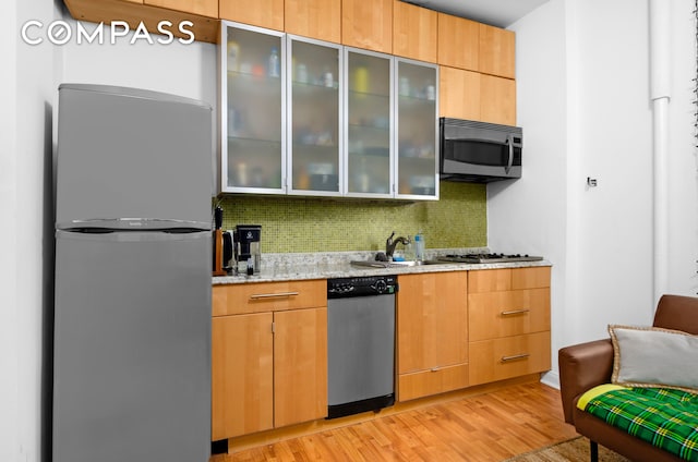 465 Eastern Pkwy Unit D, New York City, NY 11216 - kitchen featuring stainless steel appliances, decorative backsplash, light stone countertops, light wood-style flooring, and glass insert cabinets