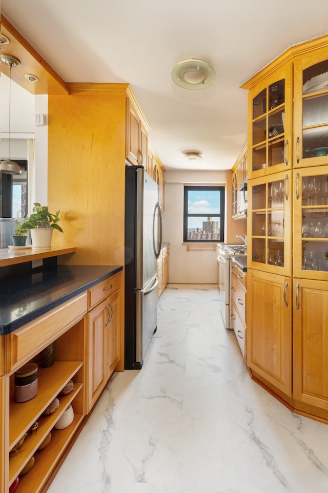 kitchen featuring freestanding refrigerator, white gas range, light marble finish floors, glass insert cabinets, and dark countertops