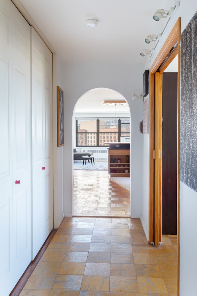 corridor with arched walkways and baseboards