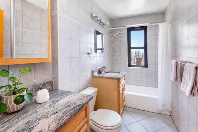 bathroom with tile walls, tile patterned flooring, shower / tub combo, vanity, and toilet
