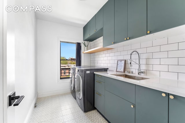 clothes washing area with washer and clothes dryer, cabinet space, baseboards, and light floors