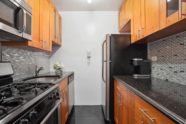 181 E 73rd St Unit 2B, New York City, NY 10021 - kitchen with appliances with stainless steel finishes, tasteful backsplash, a sink, dark stone counters, and dark tile patterned flooring