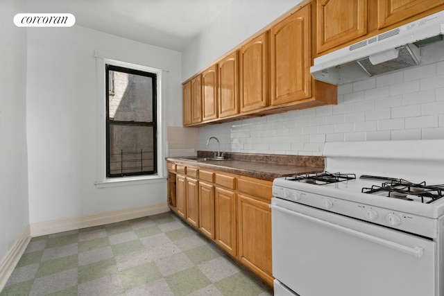 kitchen featuring white range with gas cooktop, under cabinet range hood, a sink, light floors, and baseboards