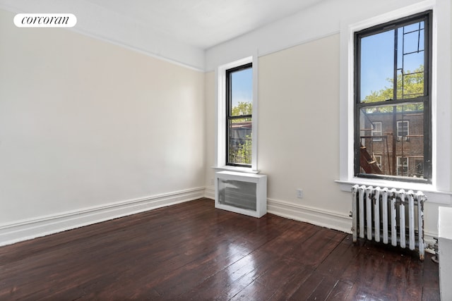 spare room with radiator, hardwood / wood-style flooring, and baseboards