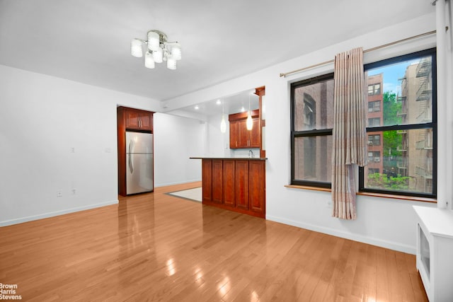 unfurnished living room featuring baseboards, light wood-type flooring, and a chandelier