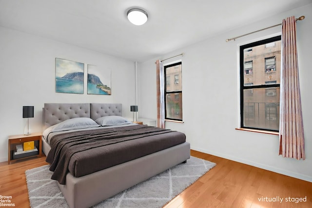 bedroom with wood finished floors, baseboards, and multiple windows