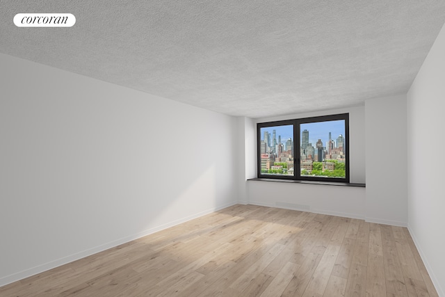 spare room featuring a textured ceiling, hardwood / wood-style flooring, baseboards, and a skyline view