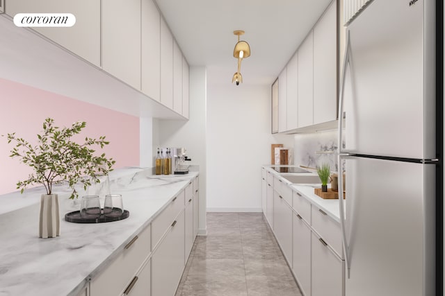 kitchen featuring freestanding refrigerator, light marble finish flooring, white cabinetry, and light stone counters
