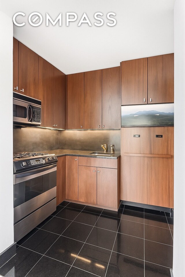 343 E 74th St Unit 15D, New York City, NY 10021 - kitchen featuring stainless steel appliances, dark tile patterned flooring, and dark countertops