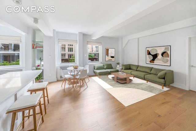 living area with light wood-style flooring and beam ceiling