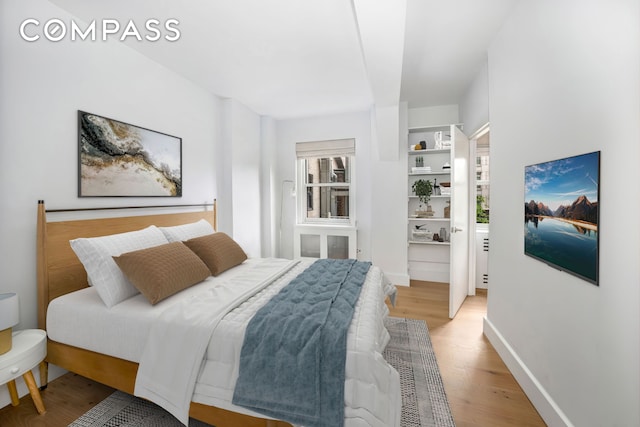 bedroom featuring light wood finished floors and baseboards