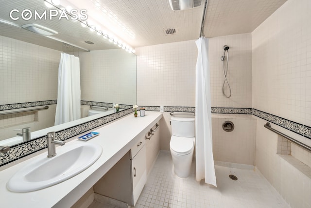 full bath featuring toilet, tile walls, tiled shower, vanity, and tile patterned floors