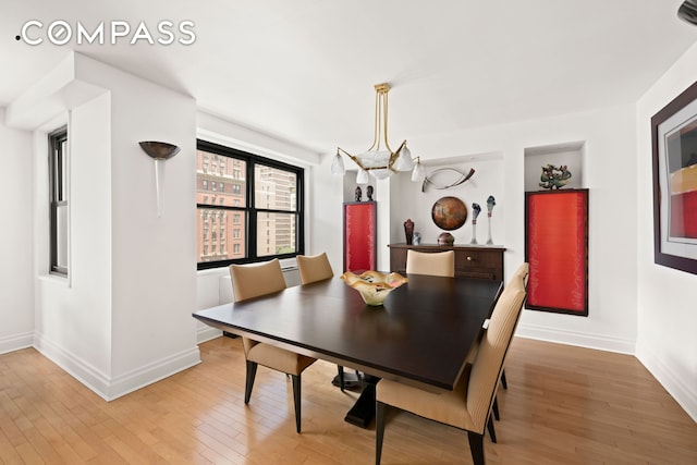 1065 Park Ave Unit 11A, New York City, NY 10128 - dining area featuring baseboards, light wood-type flooring, and a chandelier